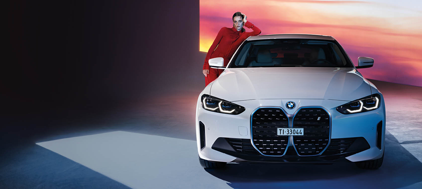 Donna appoggiata alla BMW i4 bianca in studio