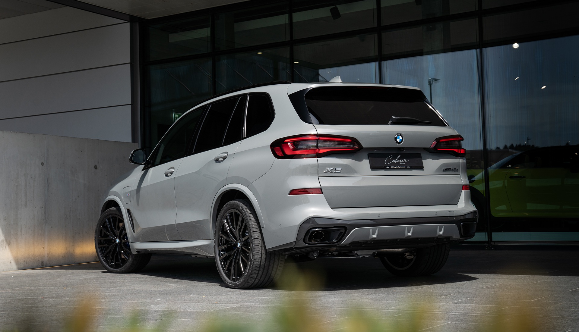 Heck BMW X5 xDrive45e Colour Edition Heck BMW X5 xDrive45e Colour Edition weiss seitlich von hinten Parkplatz Glaswand