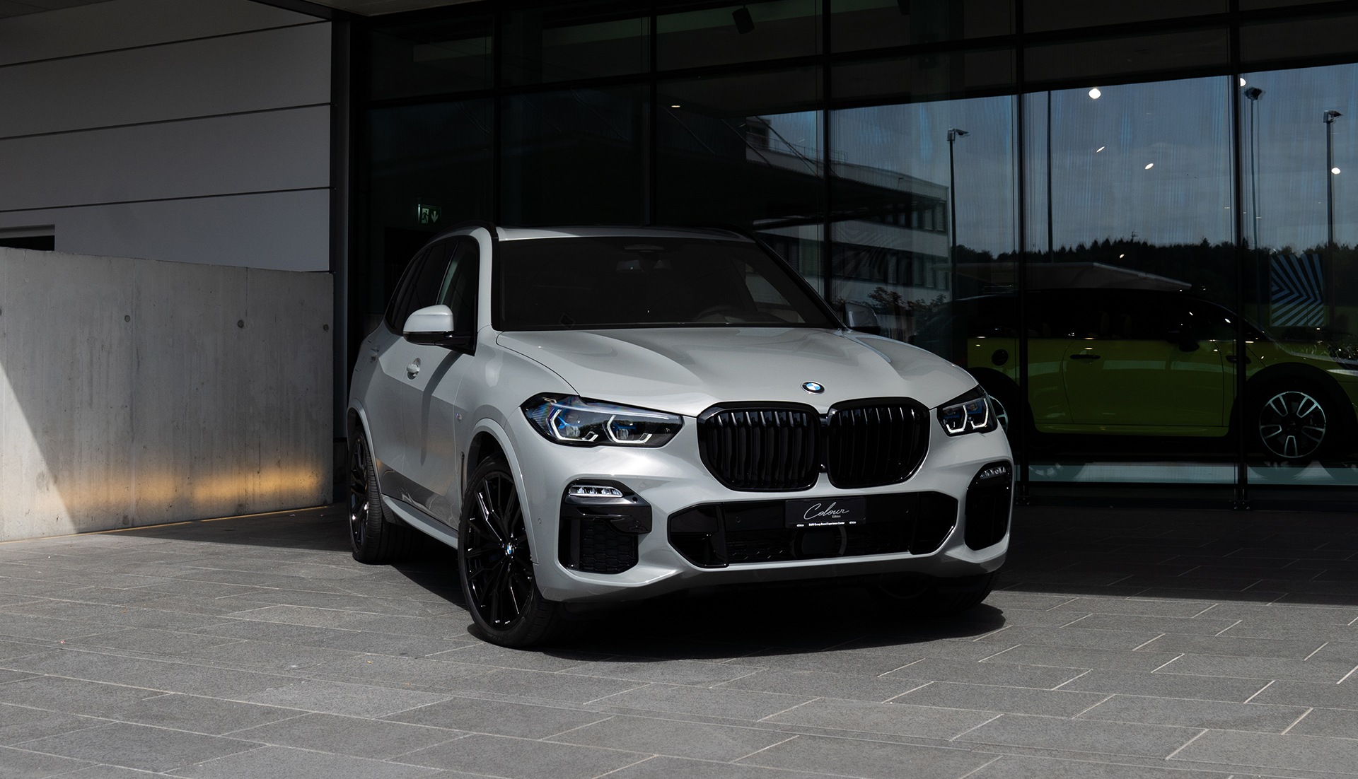 BMW X5 xDrive45e Colour Edition BMW X5 xDrive45e Colour Edition weiss seitlich von vorne Parkplatz Glaswand