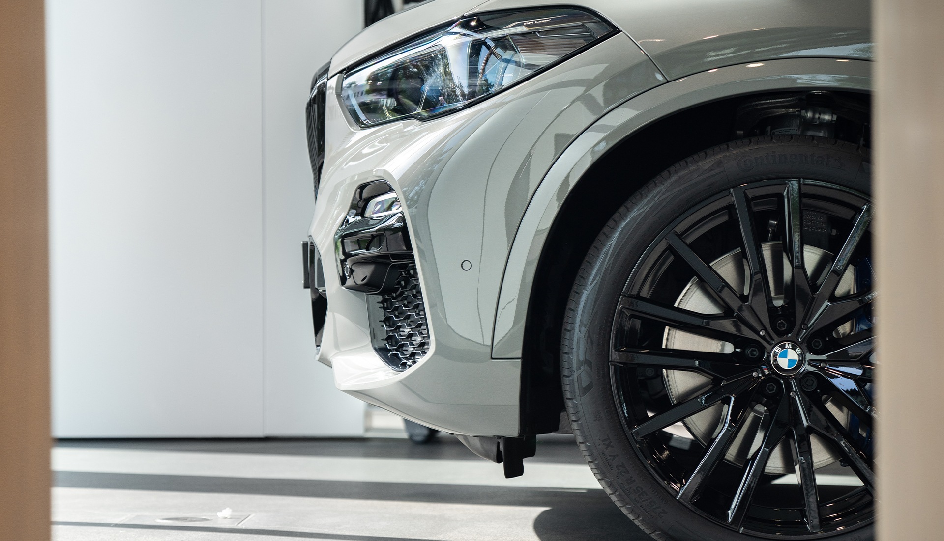 Frontpartie BMW X5 xDrive45e Colour Edition Frontpartie BMW X5 xDrive45e Colour Edition weiss Seitenansicht Parkplatz Hauswand