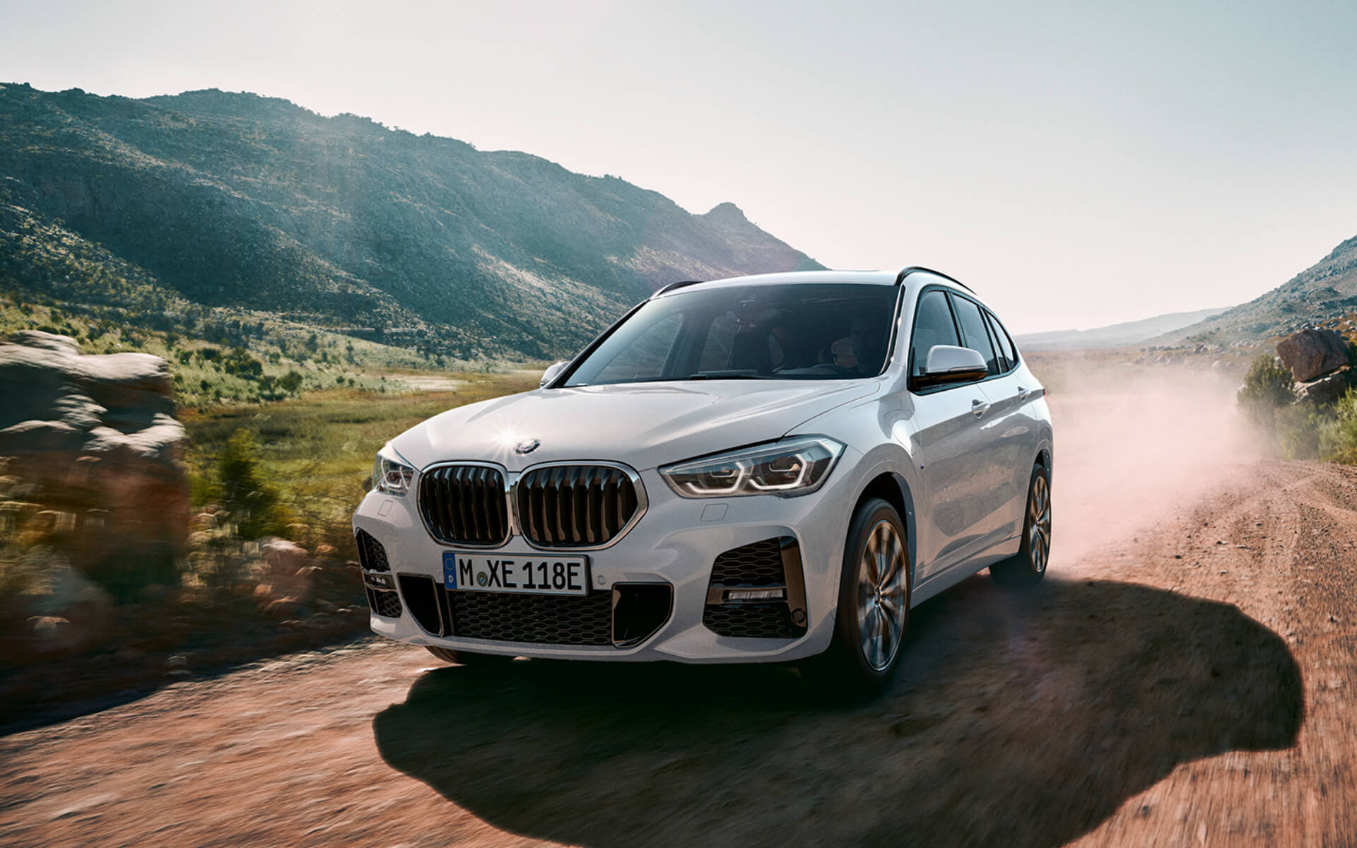 BMW/ X1/weiss/schräg von vorne/unbefestigte Strasse durch Naturlandschaft