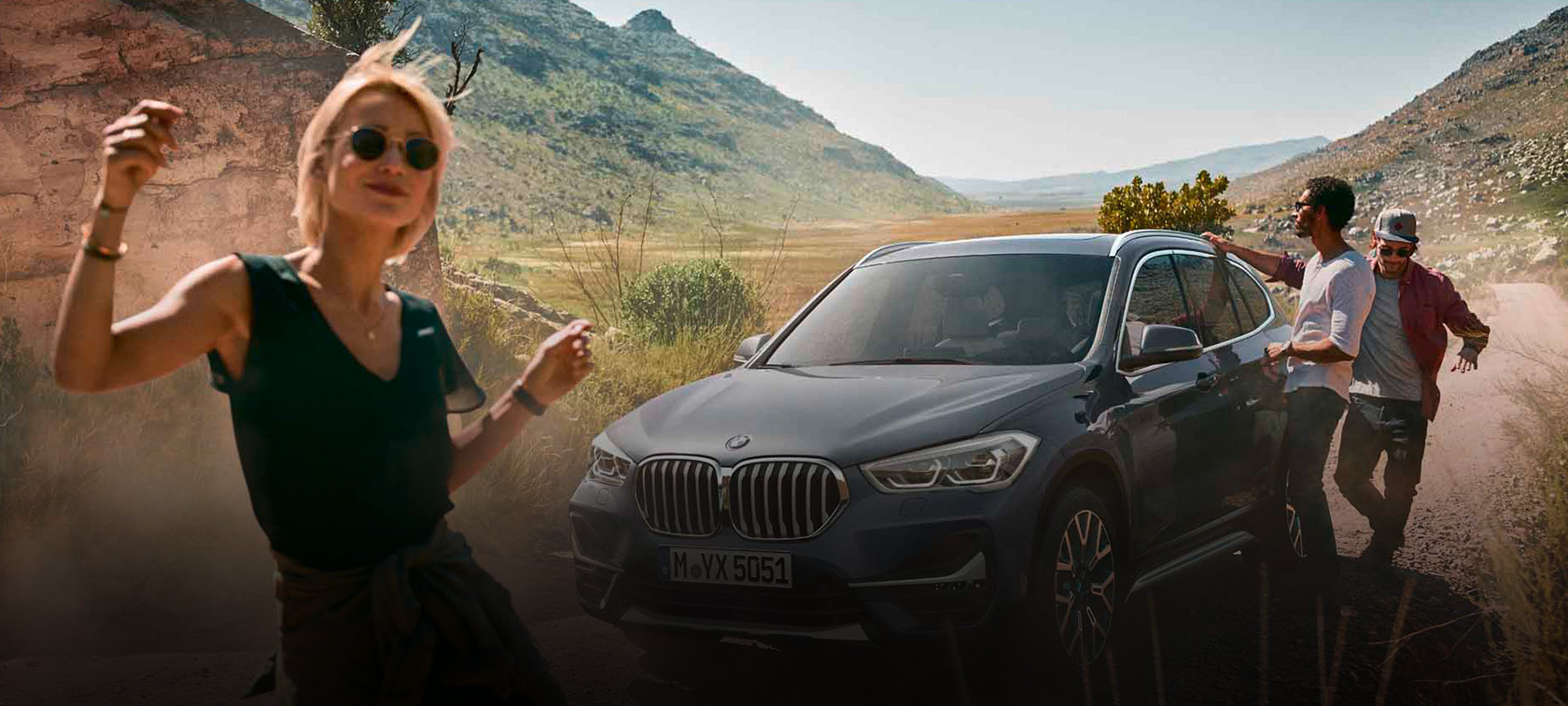 Une femme danse devant une voiture se trouvant dans un paysage désertique.