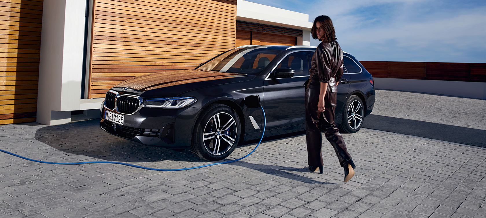 Donna BMW Serie 3 Touring ibrida plug-in Donna/BMW Serie 3 Touring/nera/laterale/stazione di ricarica/casa