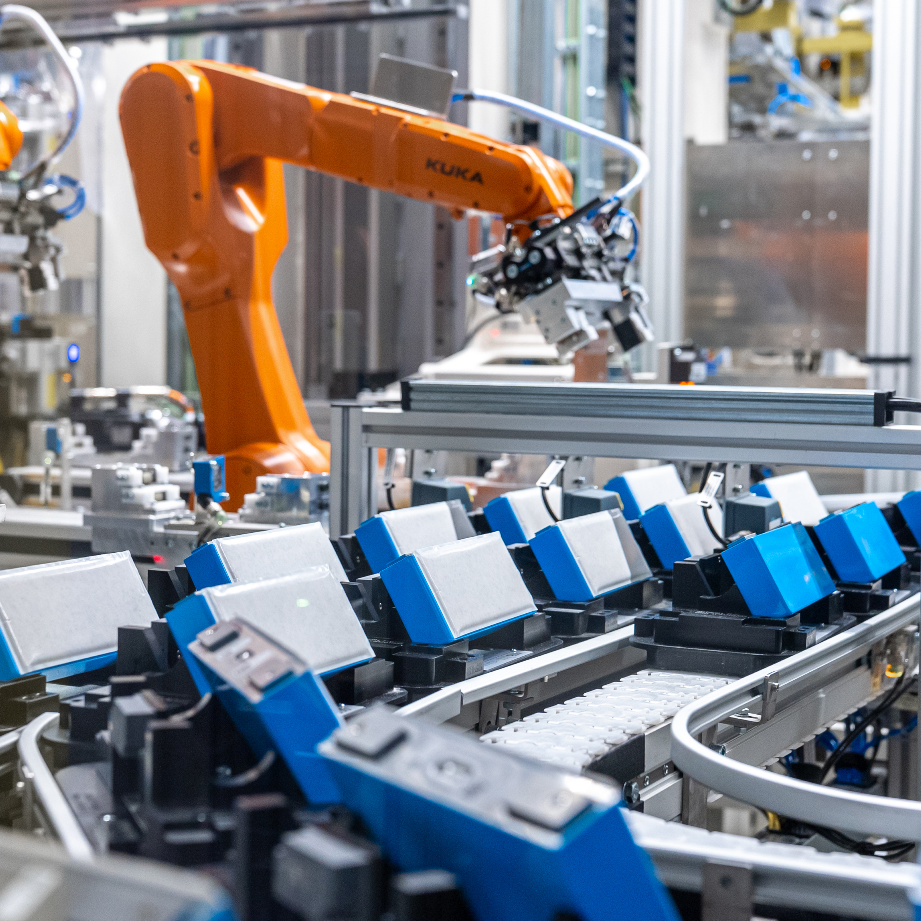 Die Nahaufnahme mehrerer blau-weisser Batterien auf einem Band im BMW Werk