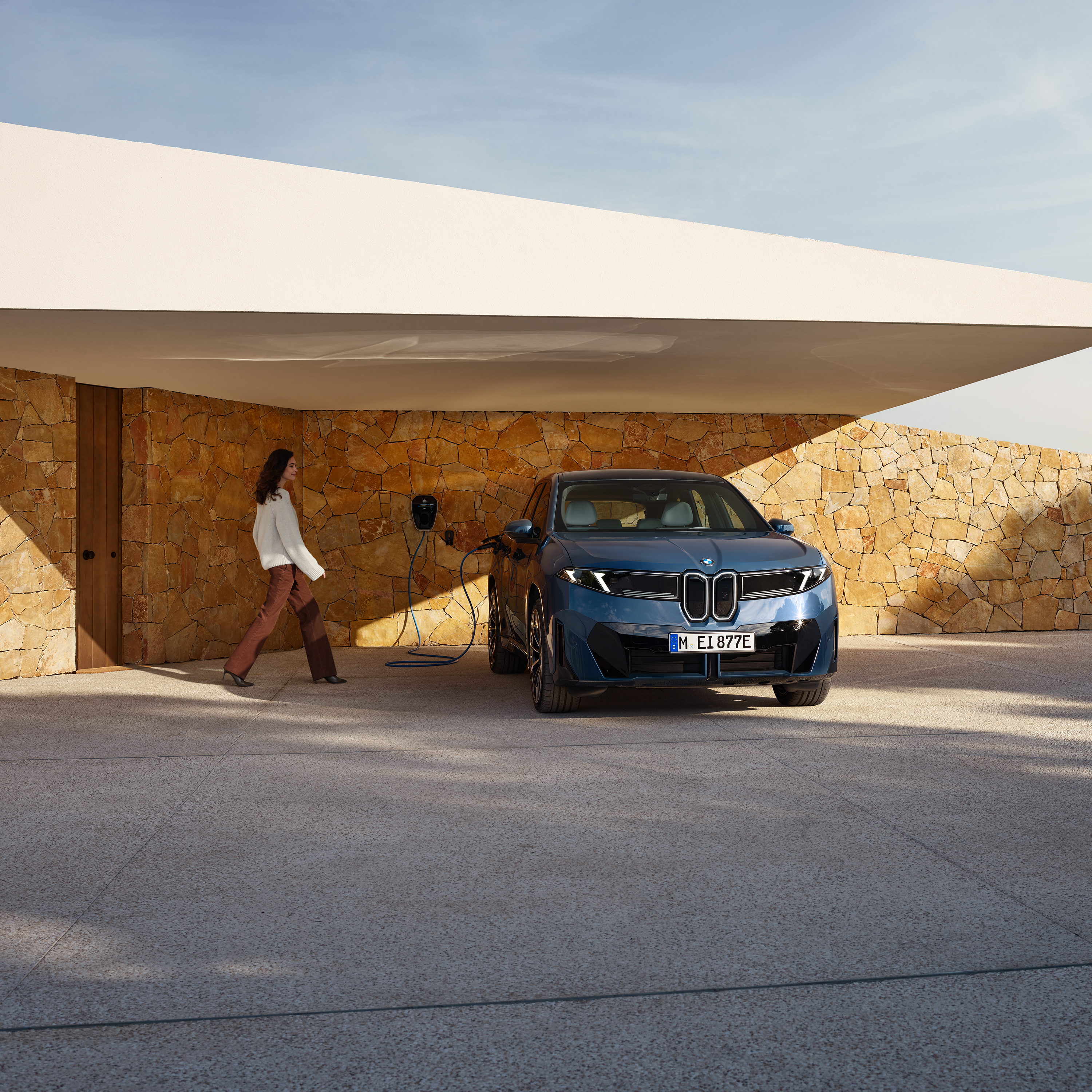 Una donna si avvicina a una BMW iX3 collegata a una Wallbox