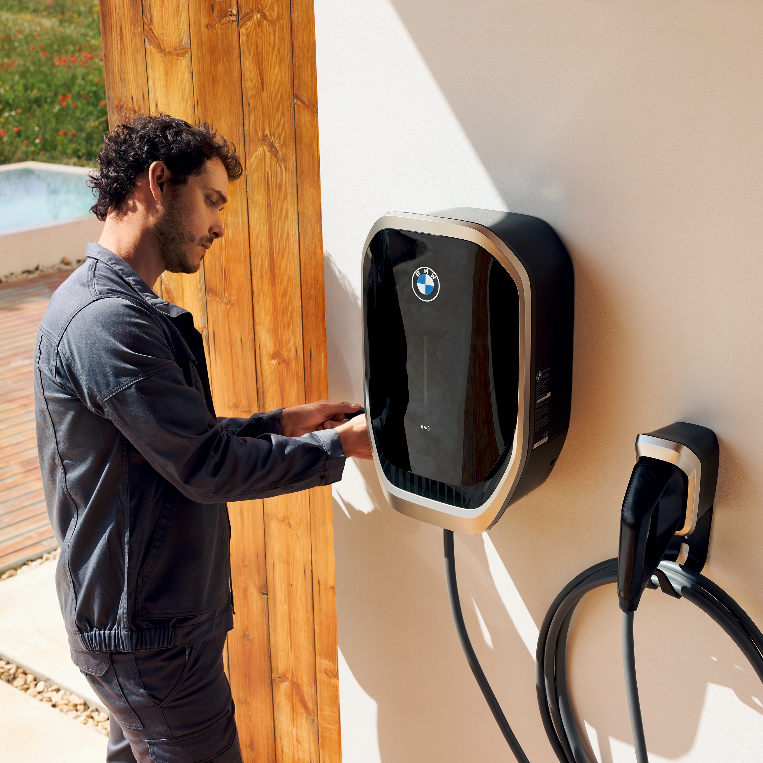 Una persona collega un cavo di ricarica a una Wallbox BMW