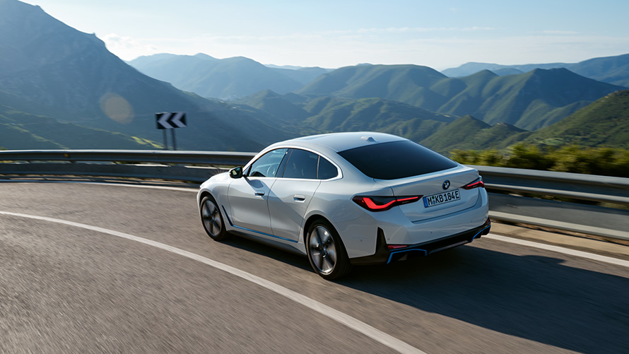 BMW i4 vista laterale di tre quarti in movimento su una strada